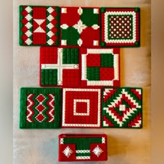 four red and green knitted coasters sitting on top of a white table cloth