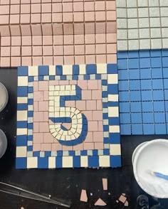 the number five is made out of tiles on the table next to bowls and utensils