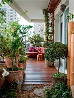 an outdoor patio with potted plants and wooden flooring, along with large windows