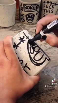 someone is painting the inside of a coffee cup with black marker and white paint on it