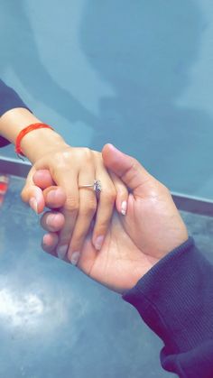 two people holding hands with one another and the other wearing an engagement ring on their finger