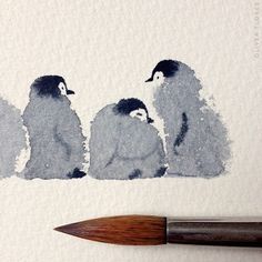 three penguins sitting on the ground next to a paintbrush