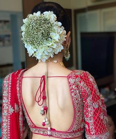 the back of a woman's head with flowers in her hair and jewelry on it