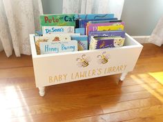 a wooden toy box filled with books on top of a hard wood floor