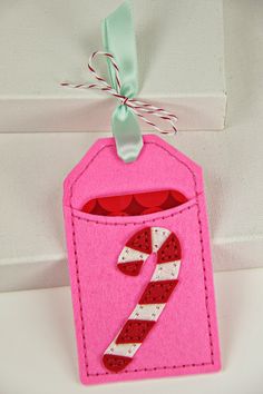 a pink felt ornament with a candy cane in the pocket and green ribbon