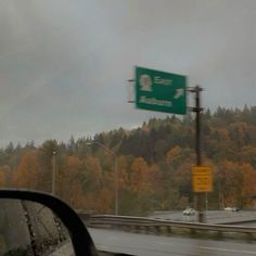 a highway sign on the side of a road with trees in the backgroud