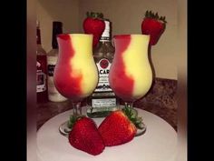 two glasses filled with liquid and strawberries on top of a table