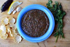 a blue bowl filled with black bean salsa next to chips and lemon wedges on a cutting board