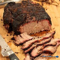 a large piece of meat sitting on top of a cutting board next to a knife