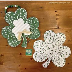 some paper shamrocks are sitting on a wooden table and one is green with white flowers