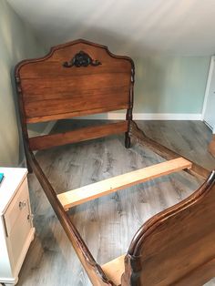 a wooden bed frame sitting on top of a hard wood floor next to a dresser