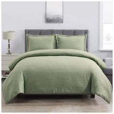 a bed with green sheets and pillows in a room