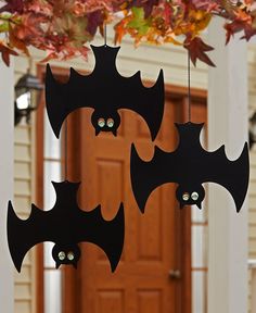 three bats hanging from a door with green eyes