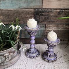 two candles are sitting next to each other on a doily with flowers in the background