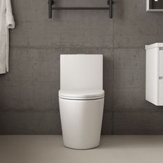 a white toilet sitting next to a wall mounted towel dispenser in a bathroom