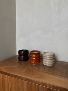 three bowls sitting on top of a wooden dresser next to a white and brown wall