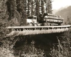 an old photo of a truck carrying logs