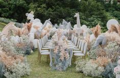 an outdoor wedding setup with white chairs and balloons in the shape of giraffes