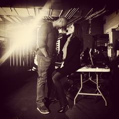 a man and woman standing next to each other in front of a table with chairs