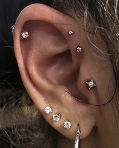 a woman's ear is adorned with small diamond studs