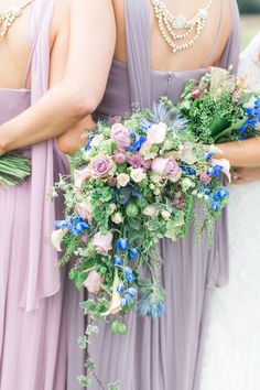 three bridesmaids in lavender dresses hold bouquets of greenery and blue flowers