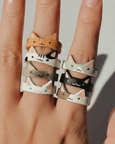 two rings that have cats on them in different shapes and sizes, sitting on someone's hand