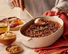 a person is spooning food out of a casserole dish on a table