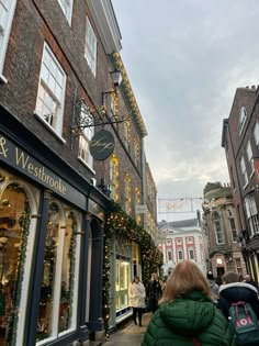 a woman walking down the street in front of a store with christmas decorations on it