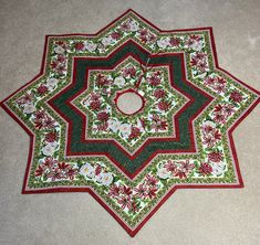 a green and red flowered table cloth on the floor with a circular hole in the center