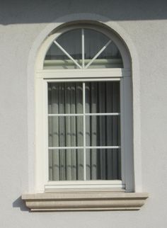 a cat sitting on the ledge of a window sill in front of a white wall