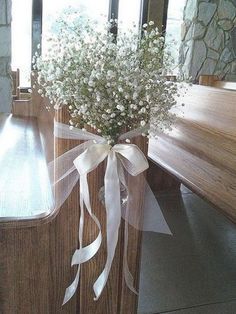 a vase filled with baby's breath sitting on top of a wooden table next to a window