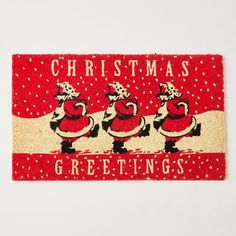 a red door mat with three santas on it and the words, christmas greetings