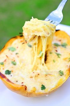 a fork is lifting up some food out of a baked potato dish on a white plate