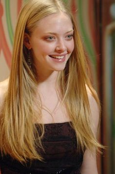 a young woman with long blonde hair smiling at the camera while wearing a strapless dress