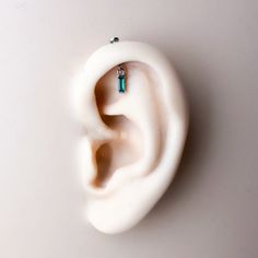 a pair of earrings sitting on top of a fake earring that is shaped like an ear