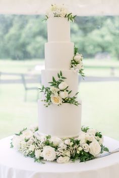 a wedding cake with white flowers and greenery