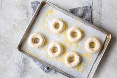 four doughnuts on a baking sheet with yellow sprinkles