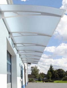 an awning on the side of a building with blue sky and clouds in the background