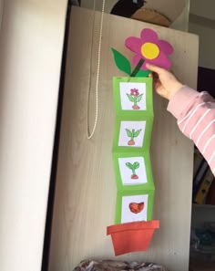 a child holding a paper flower in front of a wooden board with pictures on it