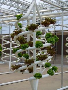 a white sculpture with green plants growing on it's sides in a building that looks like a spiral staircase