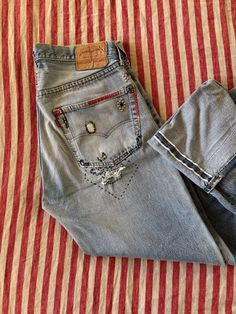 1970s/80s Levi's Redline 501s w/ Stud + Rhinestone Embellishments- 33 Awesome pair of 1970s/80s selvedge Levi's 501s with rhinestones, studs and patchwork. Likely embellished in the early 2000s and was sold at a Los Angeles boutique called, "Theodore". Original tag is still attached. Has a nice, long inseam to cuff. Great vintage condition. Marked a 35x40. True measurements are below.  Measurements: Waist: 33" Rise: 11.75" Hip: up to 43" Inseam: 36" Levi 501s, Rhinestone Embellishments, The Early 2000s, Womens Jeans, Early 2000s, 1970s, Embellishments, Women Jeans, Cuff