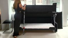 a woman standing in front of a couch with a bed frame on top of it