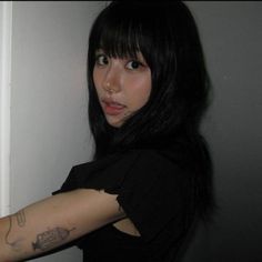 a woman with tattoos on her arm leaning against a wall