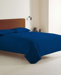 a bed with blue sheets and pillows in a room