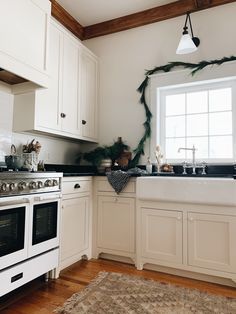 a kitchen with white cabinets and black counter tops is decorated with greenery for the holiday season