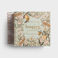 a spiral notebook with the words inspire written on it and an illustration of flowers in orange,