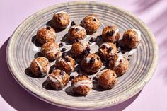 a plate full of doughnuts with icing and chocolate chips on top, sitting on a purple surface