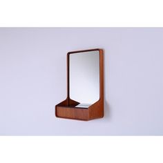 a mirror mounted to the side of a wall next to a wooden shelf with a drawer underneath it