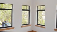 three windows in a white room with wood trim around them and one window has black panes