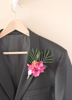 a black suit with a pink flower on it and a hanger in the background